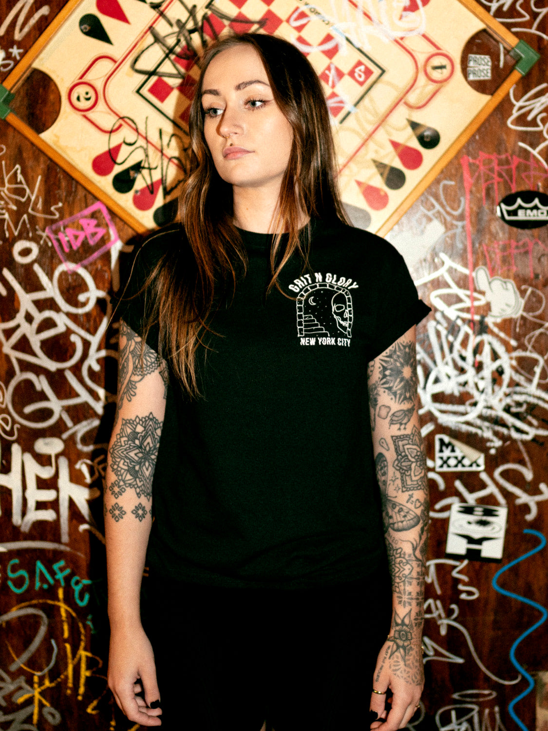 A person wearing the If Lost graphic tee featuring a small front chest graphic with skull and sky portal design. Text reads Grit N Glory New York City. 