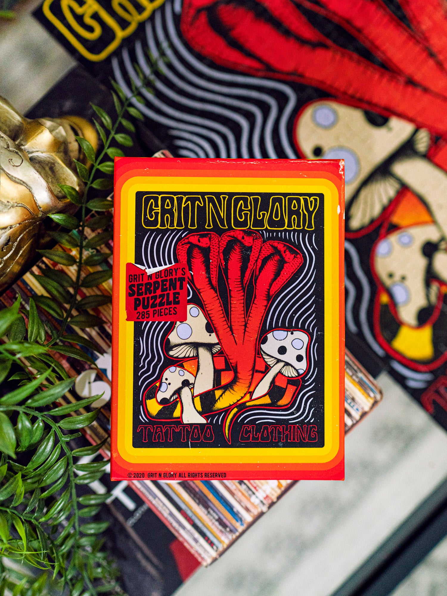 A puzzle box with a yellow and black multi headed cobra design, featuring the text 'Serpent Puzzle' and 'Grit N Glory'.