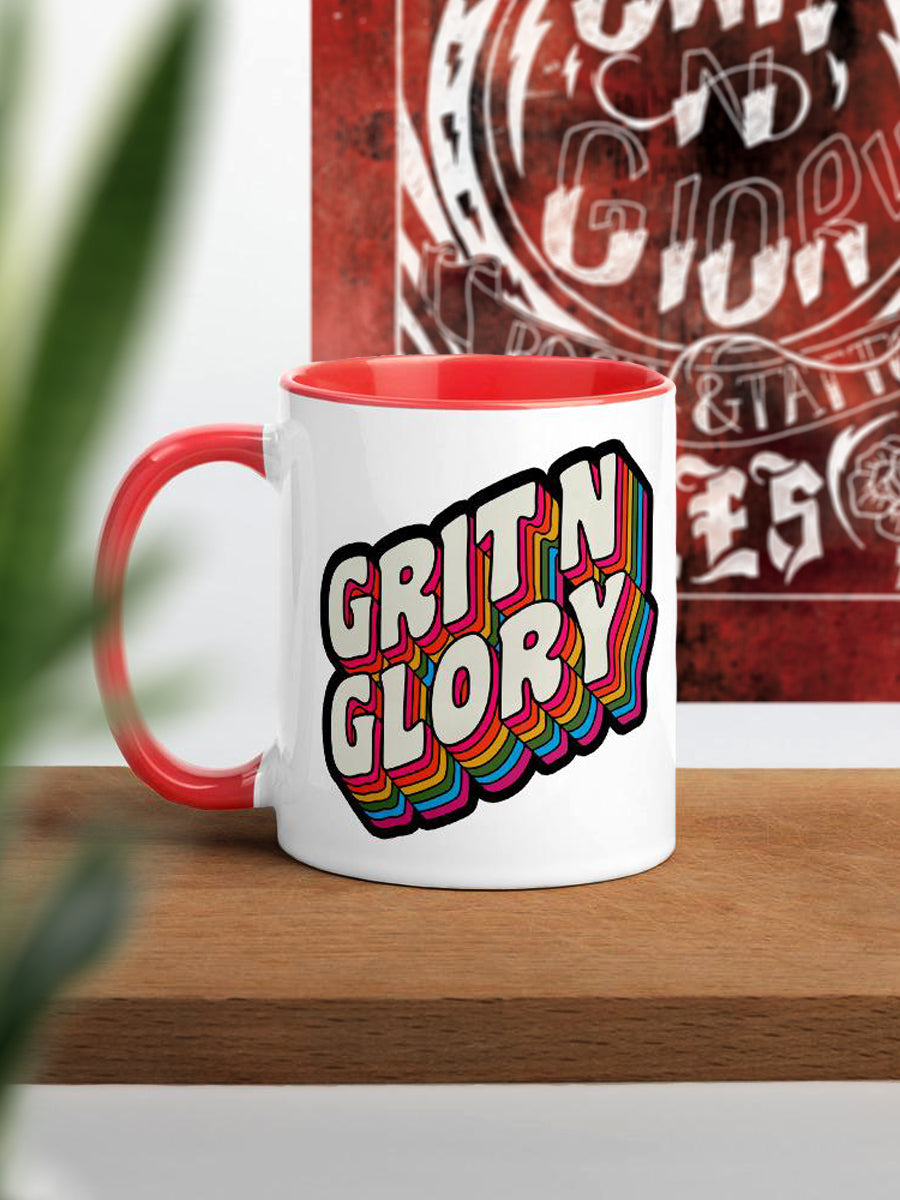A white and red ceramic mug with a colorful 'Grit N Glory' logo print.